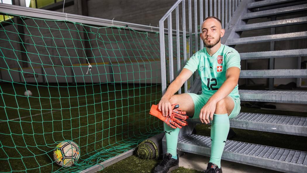 «Ich liebe die Goalie-Position» Patrick Allenbach sitzt im Fussballtenue auf einer Treppe in einer Sporthalle, offener Blick in die Kamera, Goalie-Handschuhe in der Hand