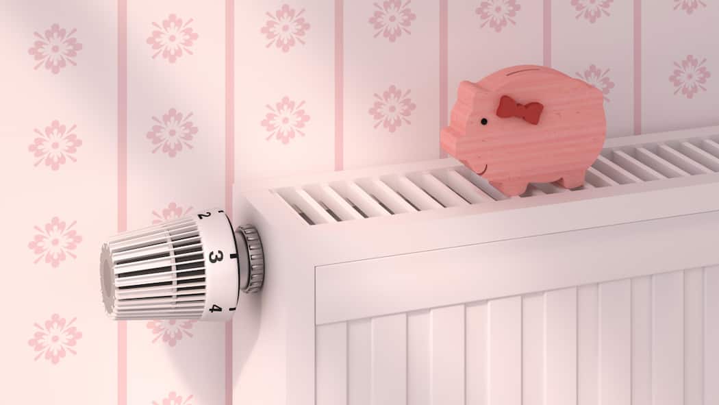Frieren zum Sparen? Das muss nicht sein Ein pinkfarbiges Holzsparschwein steht auf einem Heizkörper.