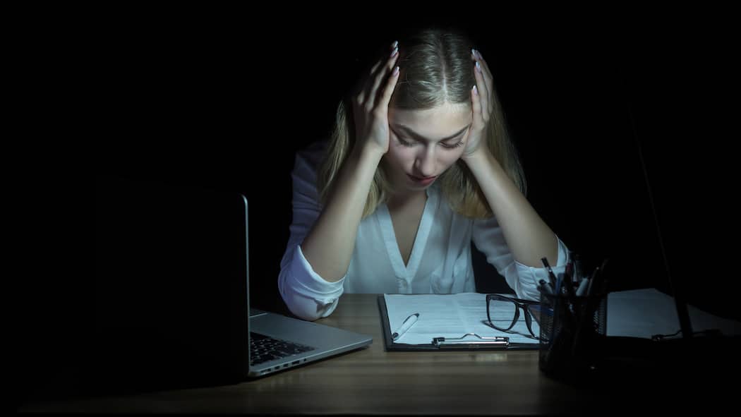 Immer Ärger mit dem Zeugnis Geschäftsfrau starrt in der Dunkelheit auf Unterlagen auf Tisch