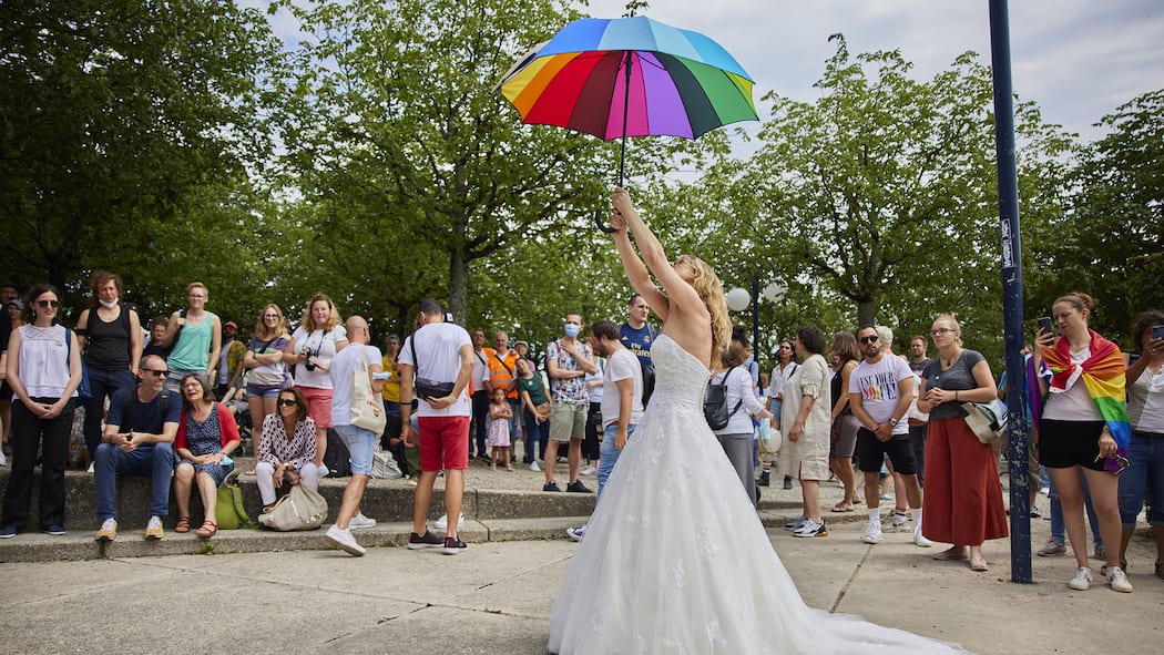 Darum geht es bei der «Ehe für alle» Frau in Hochzeitskleid hält in Lausanne bunten Regenschirm in die Luft