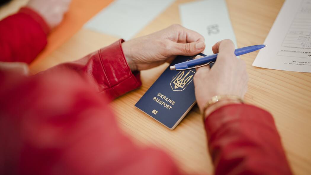 So werden ukrainische Angestellte in der Schweiz besteuert Frau hält ukrainischen Pass beim Ausfüllen der Registrierungsformulare im Bundesasylzentrum Zürich