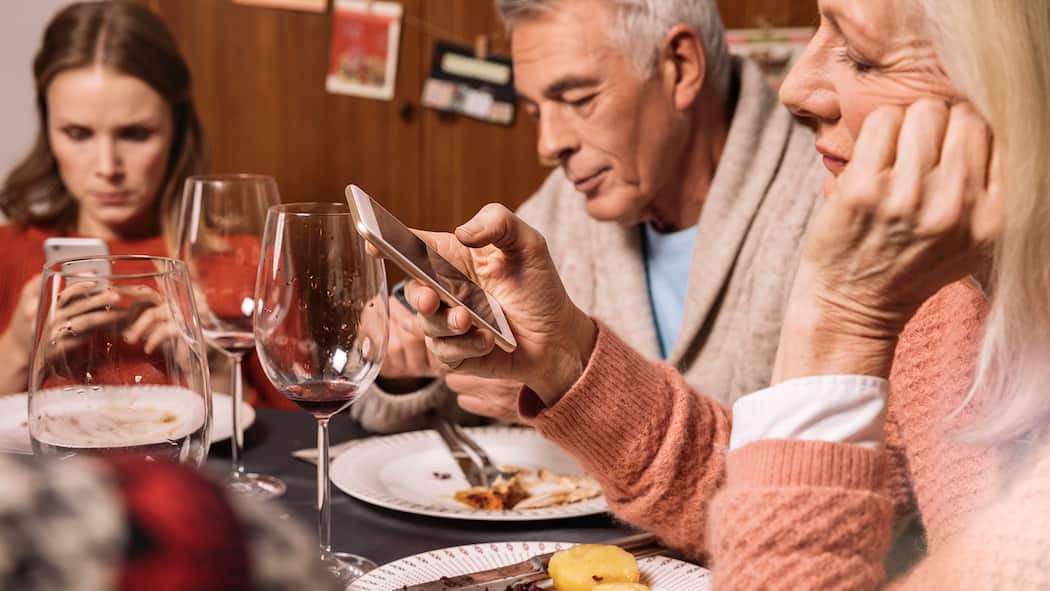 Krach beim Fest der Liebe Eine Familie sitzt an Weihnachten am Esstisch und schaut gelangweilt auf die Handys.