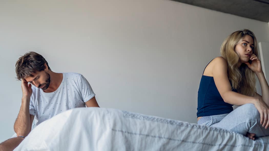 «Ich habe keine Lust auf Sex» Ein Paar sitzt auf dem Bett und dreht sich gegenseitig den Rücken zu.