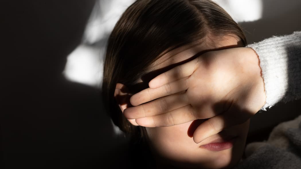 Emilia hat Angst Mädchen in halbdunklem Raum hält sich den Arm vor die Augen. Panikattacken, Depressionen, Selbstverletzungen – psychische Störungen bei Kindern und Jugendlichen nehmen zu. Ebenso verlängern sich die Wartezeiten bei Psychologinnen und psychiatrischen Einrichtungen. Warum?