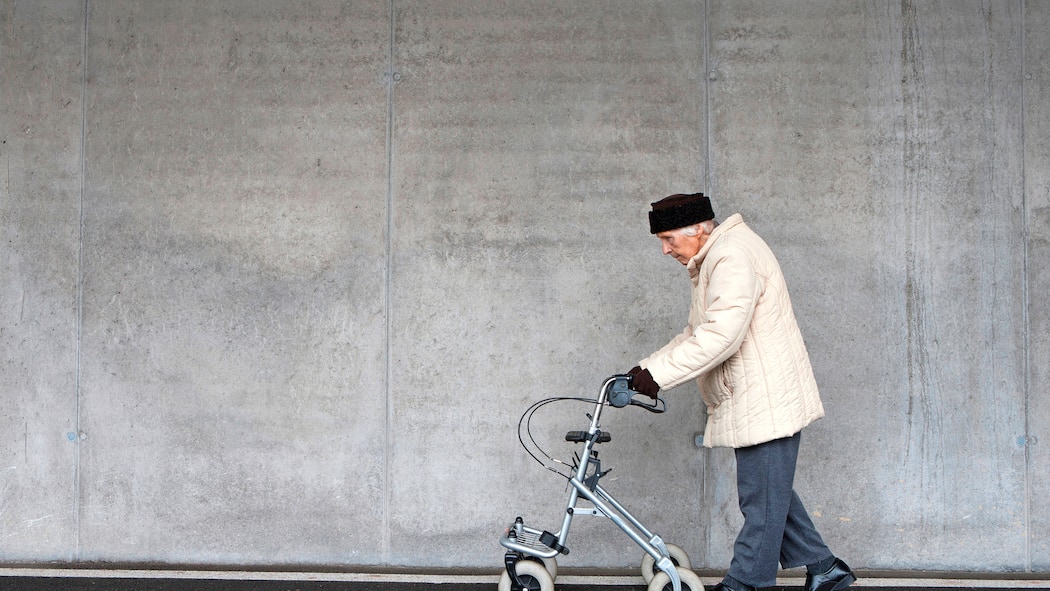 Wer hilft, zusätzliche Kosten zu decken? Alte Frau geht an Rollator