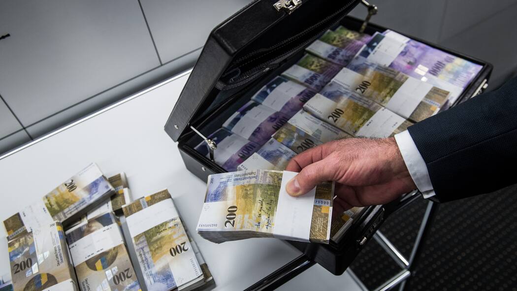 So haben Schweizer Gerichte zu Enteignungen entschieden Ein Mann füllt einen Aktenkoffer mit Tausender- und Zweihundert-Franken-Noten.