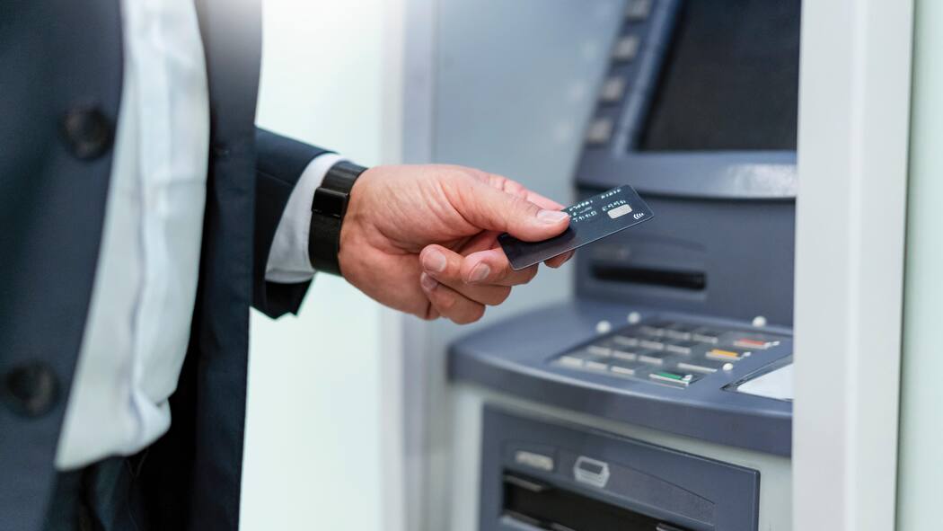 Bankgebühren zu hoch – das können Sie tun Ein Mann hebt Geld am Geldautomaten ab