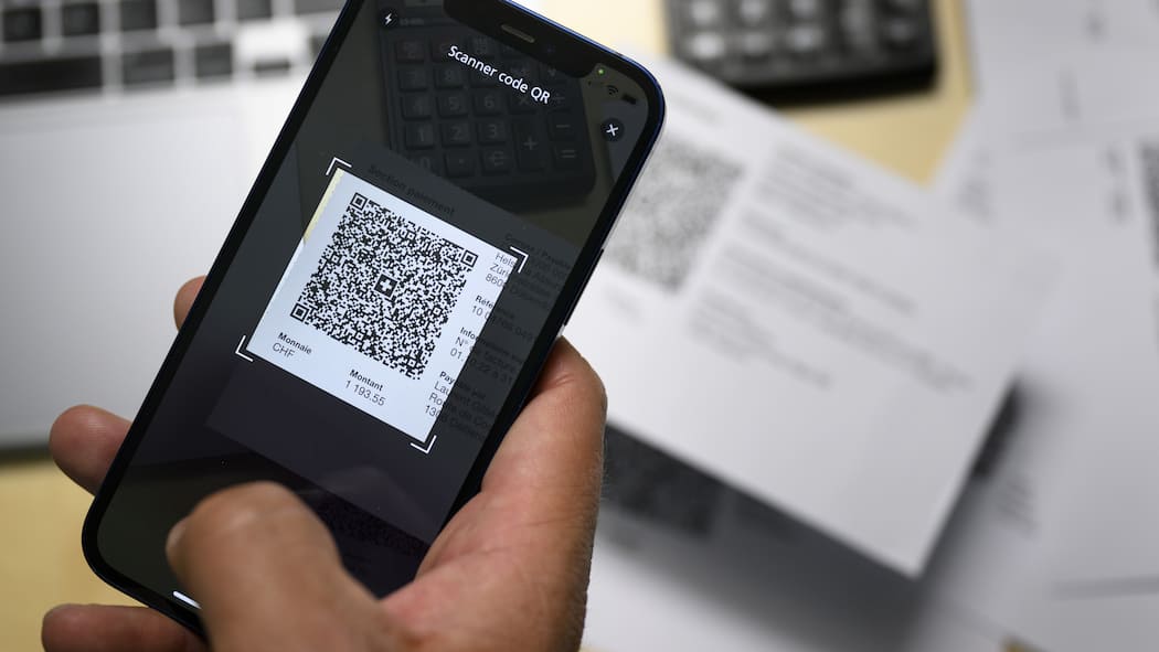 Falsche Rechnungen und Werbefallen – Kriminelle tricksen mit QR-Codes Eine Person scannt mit dem Smartphone eine QR-Rechnung