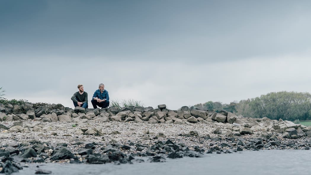 «Nichts tun ist immer falsch» Zwei Männer sitzen an einem Fluss und diskutieren miteinander.