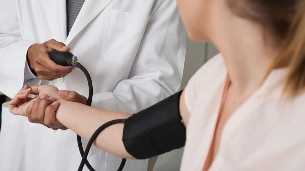 Lautlose Gefahr Ein Arzt misst den Blutdruck einer Frau.