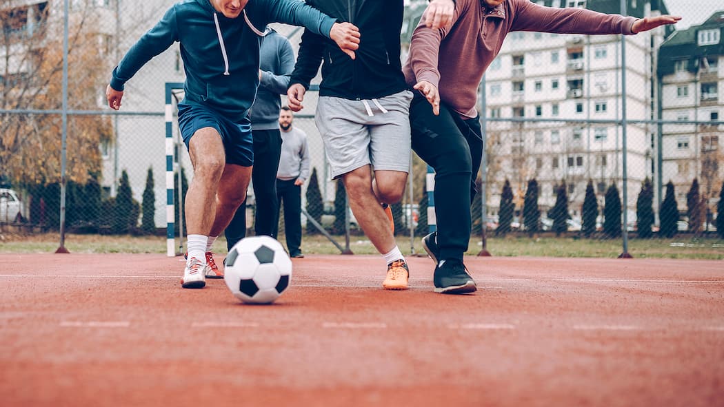 Gefährliche Freizeit für die Gelenke Ein Paar Männer spielen zusammen Fussball.