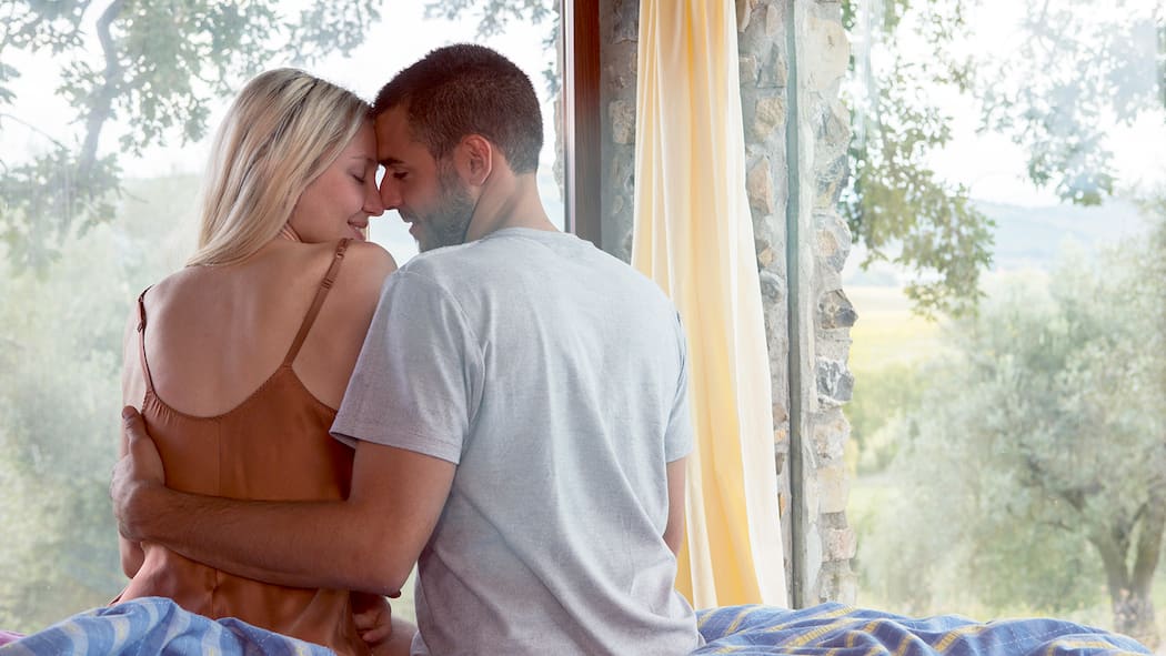 Frieden schliessen mit dem Körper – für guten Sex Ein junges Paar sitzt in einem intimen Moment auf der Bettkante.