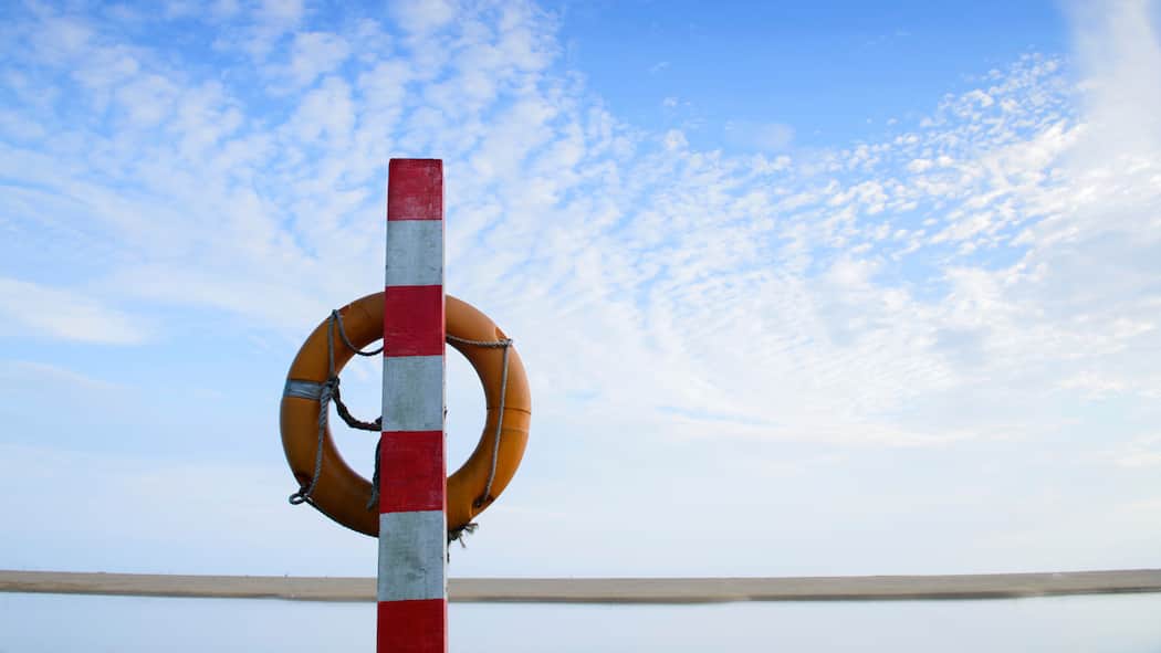 Wer zahlt die Annullierungskosten? Bild eines Rettungsrings am Strand.