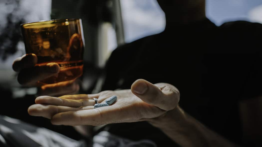 Schweizer Onlineshop verkaufte gepanschte Potenzpillen A man holds two blue tablets in his hand.