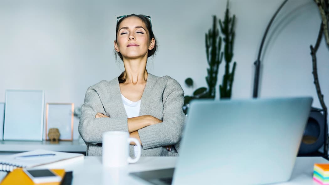 Langsam atmen – schnell entspannen Entspannte Frau am Arbeitsplatz