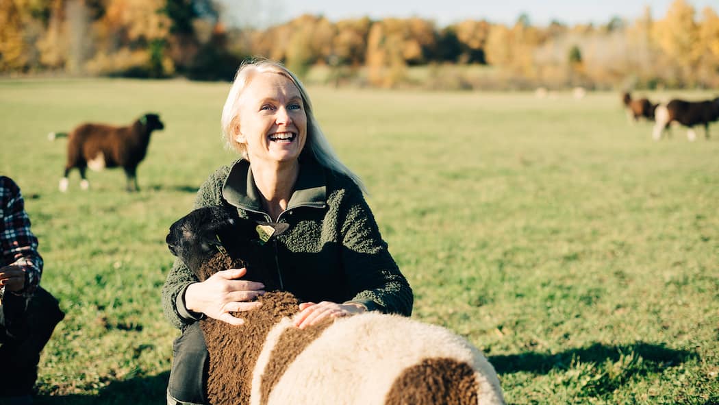 Ist es sinnvoll, eine Auszeit zu nehmen? Eine Frau mittleren Alters hält ein Schaf im Arm.