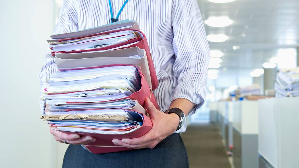 Riesenpleite, aber keine Eile Mann trägt Aktenstapel