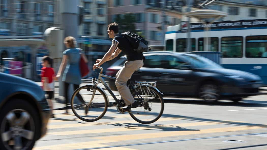 Müssen Velos immer auf dem Veloweg fahren? Ein Velofahrer fährt über einen Fussgängerstreifen. Was im Strassenverkehr für Velofahrer gilt.