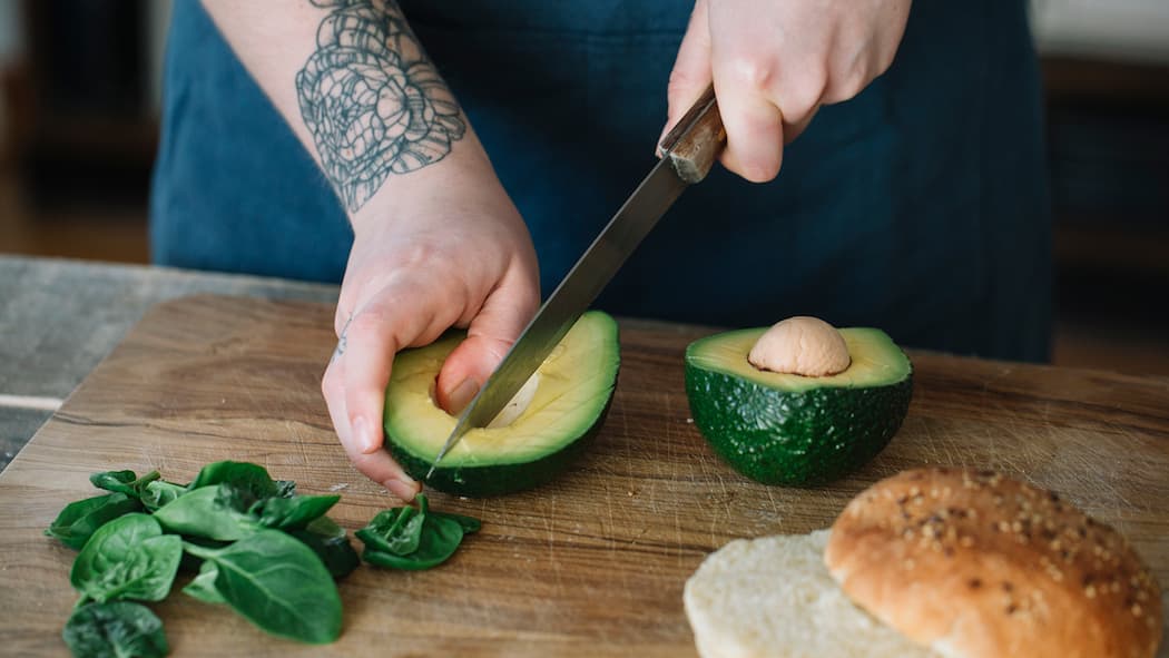 Glykämischer Index Eine Frau schneidet eine Avocado auf.