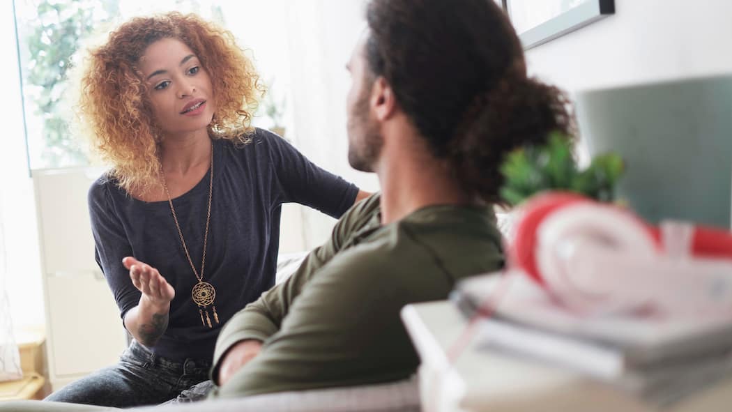 «Reife Liebe braucht Arbeit» Ein junges Paar sitzt zu Hause auf dem Foto und führen eine angespannte Diskussion.