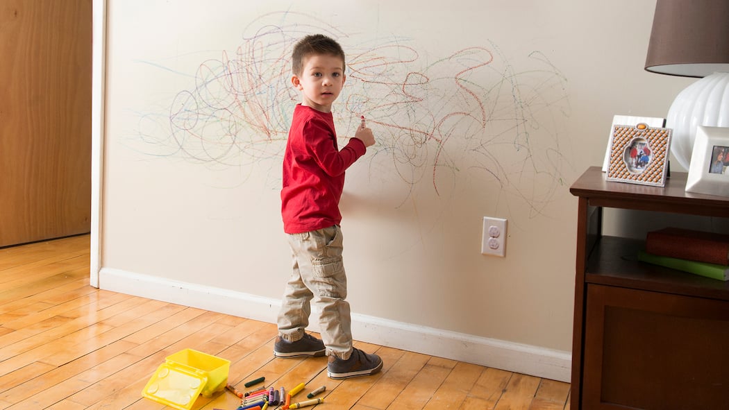 Wer zahlt Schäden in der Mietwohnung? Ein kleiner Junge wird dabei ertappt, wie er an die Wand des Wohnzimmers zeichnet.