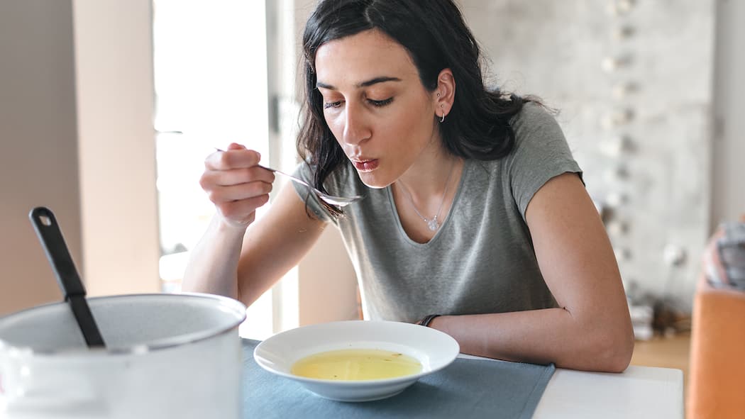 Das sollten Sie essen, um schneller gesund zu werden Eine Frau mit Grippe isst eine Suppe. Bei Erkältung und Grippe hilft es, die Ernährung ein wenig anzupassen.