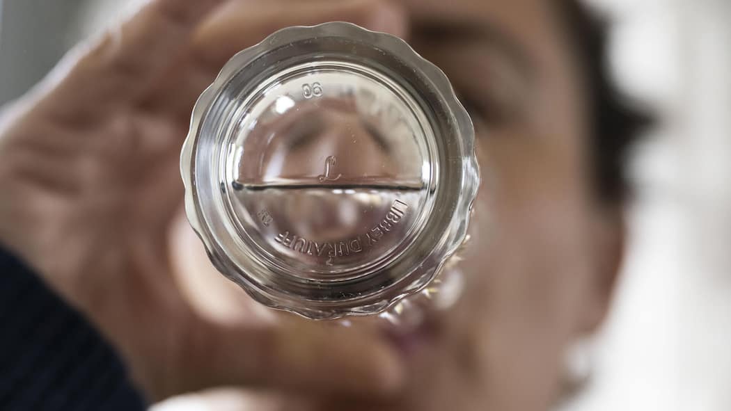 Verunreinigtes Trinkwasser belastet die Gemeinden immer mehr Mann trinkt Wasser, Blick von unten durchs Wasserglas - Für Schweizer Gemeinden wird die Trinkwasseraufbereitung zum Problem. Sie fordern finanzielle Unterstützung vom Bund, doch dieser hat andere Pläne
