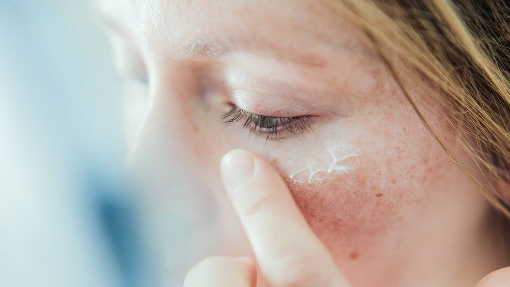 Welche Seifen und Cremen passen zu meinem Hauttyp? Frau cremt sich vor dem Spiegel ein