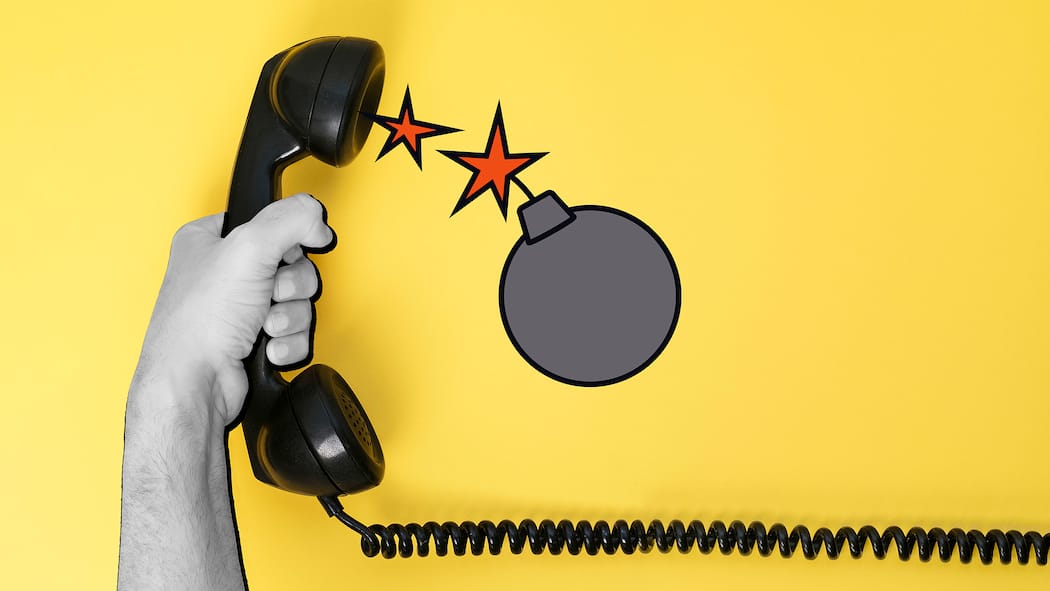 Hier spricht nicht die Polizei! Eine Hand hält einen Telefonhörer, aus dem eine Bombe springt. Telefonbetrüger rufen oftmals als falsche Polizisten an und setzen ihre Opfer unter Druck, mit dem Ziel Geld oder sensible Daten zu stehlen. Das können Sie tun, wenn Sie jemand versucht reinzulegen.
