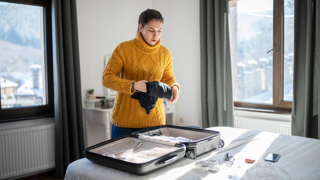 Zwei Wohnorte sind oft billiger Eine junge Frau packt ihren Koffer.