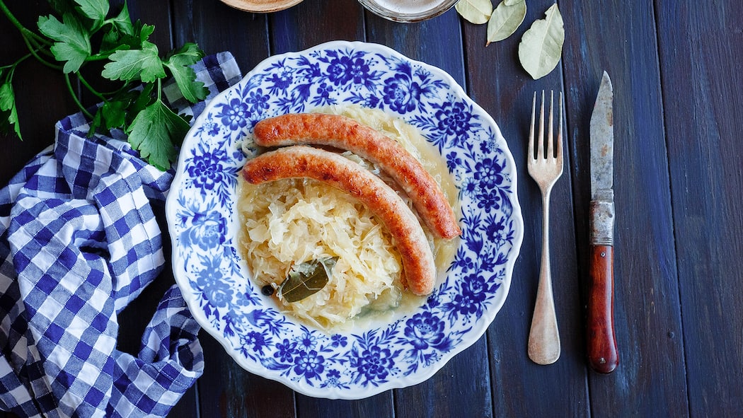 Gesund mit Sauerkraut und Kürbis Ein Teller mit Sauerkraut und Würsten von oben.