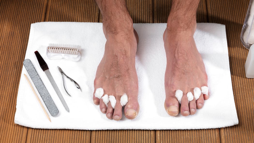 Wie man die Füsse pflegen sollte Ein Mann hat Nagelschere und Feile bereitgelegt, um die Füsse zu pflegen.