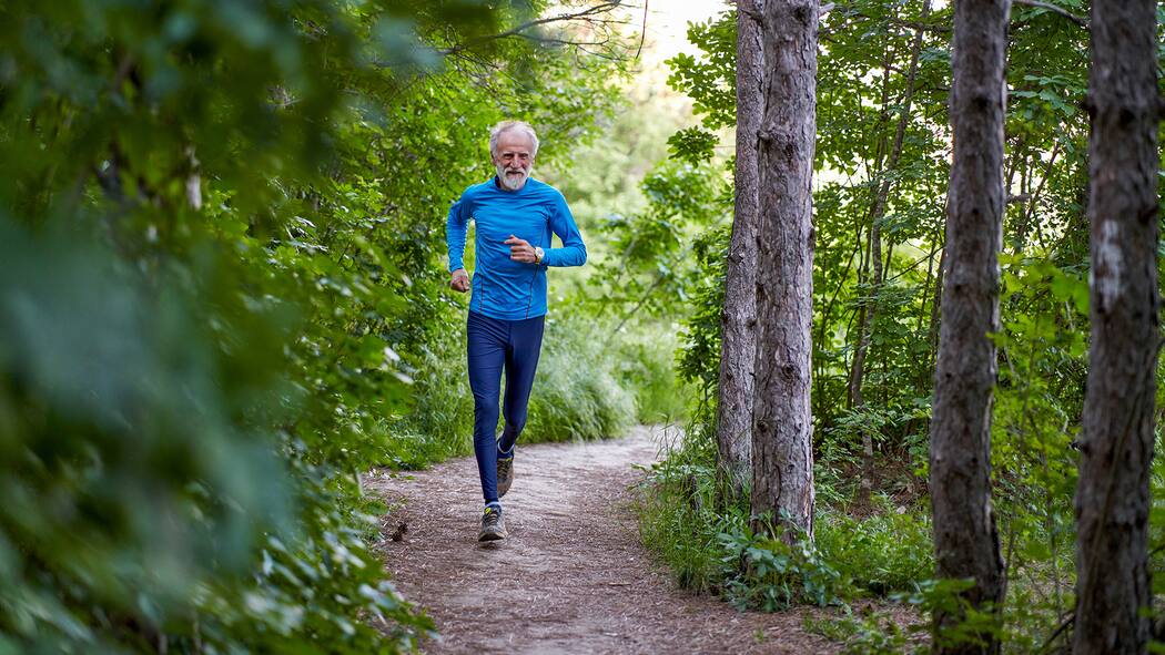 Bewegung ist die beste Prävention Ein älterer Mann joggt durch den Wald.