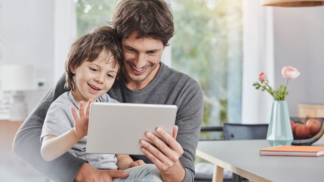 Gefahr durch Werbevideos und In-App-Käufe Vater spielt mit Sohn am Tablet