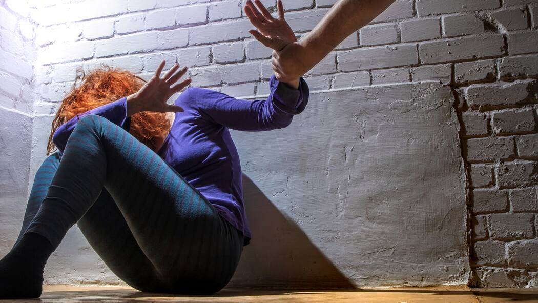 «Man kann sie nicht präventiv wegsperren» Eine Frau sitzt auf dem Fussboden und hält schützend ihre Hand vors Gesicht während eine andere Hand sie zu schlagen versucht.