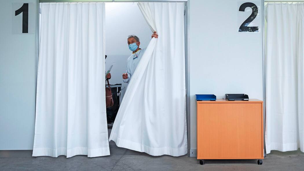 Was man von den noch nicht zugelassenen Impfstoffen erwarten kann Mann tritt hinter Vorhang hervor im Impfzentrum in Sitten