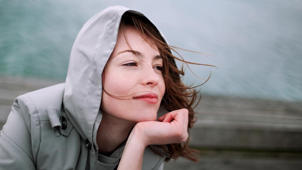 Wie Sie die innere Ruhe finden können Achtsamkeitsübungen: Eine Frau sitzt draussen und spürt den Wind.