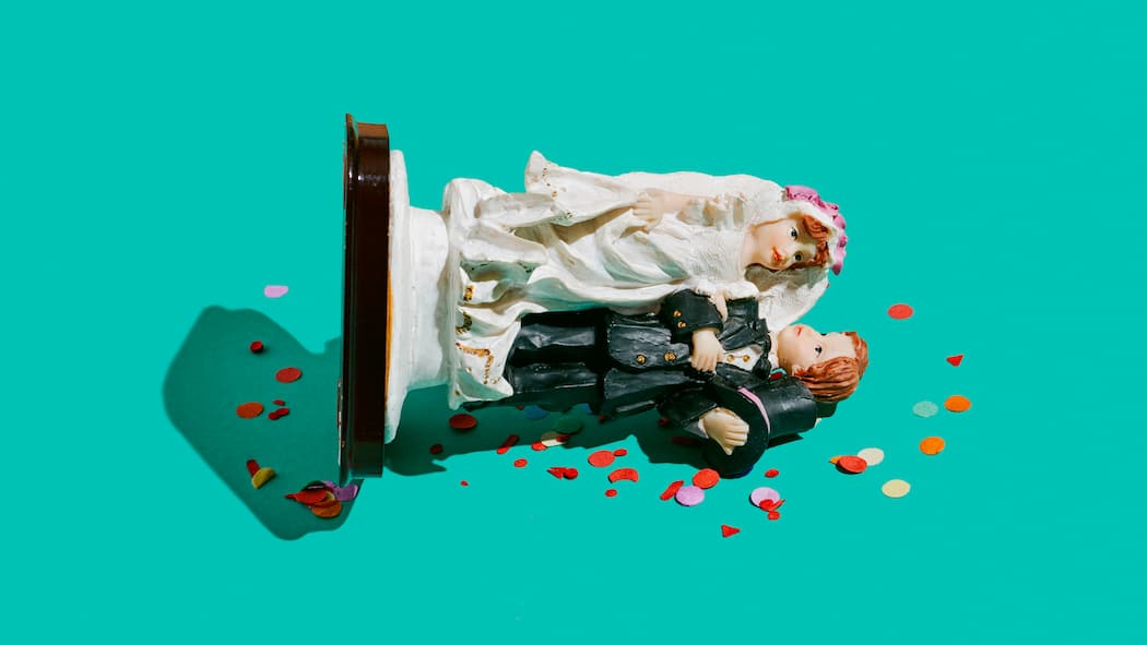 Wie Frauen im Fall einer Scheidung vorsorgen Eine Tortenfigur mit einem Ehepaar liegt umgekippt auf einer grünen Fläche.