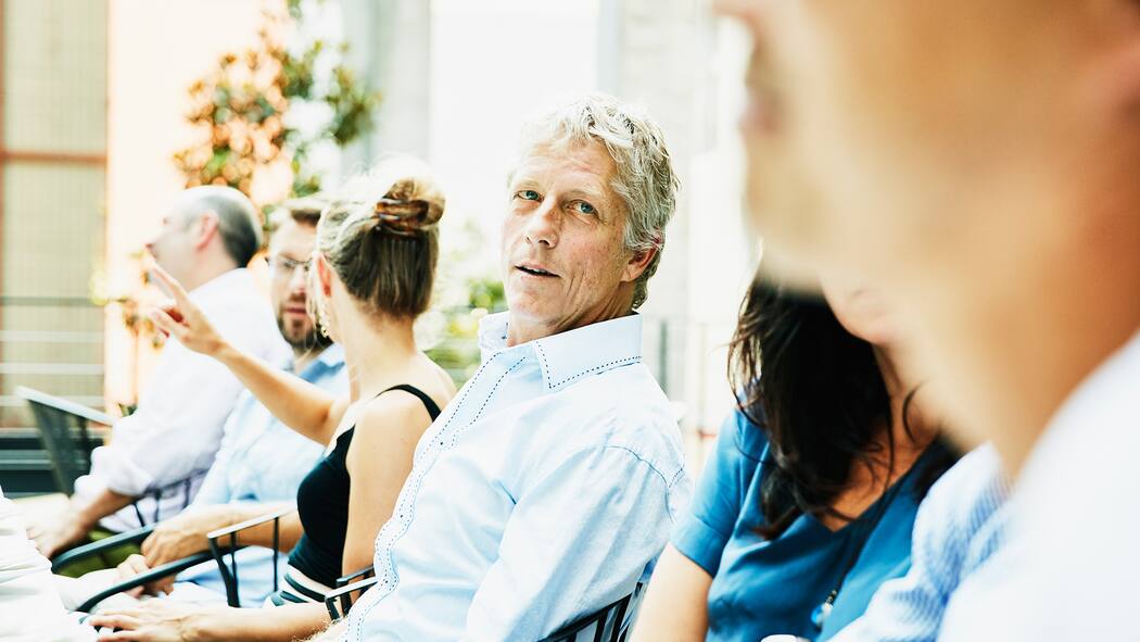 Wie wieder ins Gespräch kommen? Mann an Fest blickt nachdenklich zu anderem Mann
