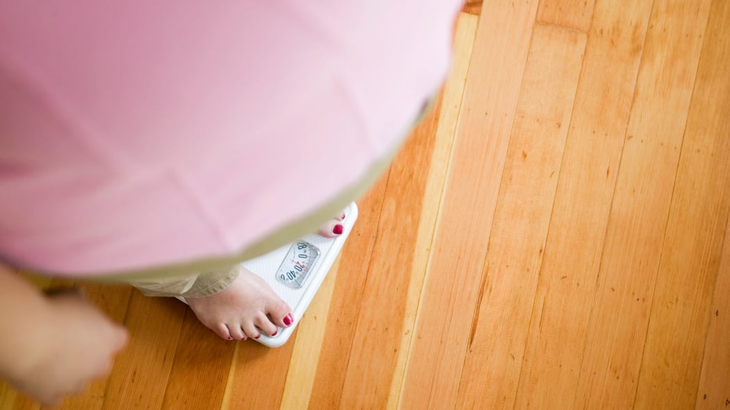 Wenn Sie Ihre Pfunde satt haben Eine übergewichtige Frau steht auf der Waage.