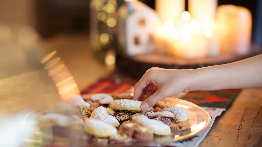 Geniessen ohne Reue Eine Frau nimmt einen Vanillekipfel von einer Platte mit Guetzli.