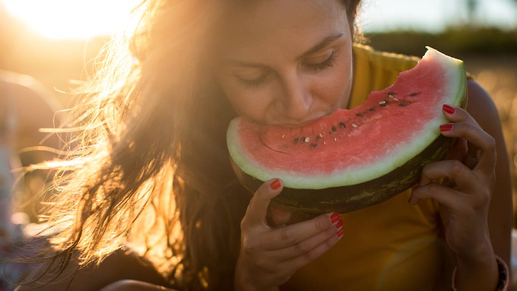 Coole Rezepte für heisse Tage Frau beisst in Wassermelone