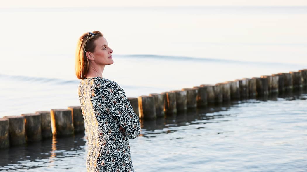 Wie der Atem die Haltung positiv beeinflusst Frau atmet am Wasser