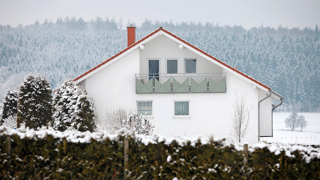 Wie werde ich Vermieterin? Ein Einfamilienhaus auf dem Land, umgeben von verschneiten Wäldern.