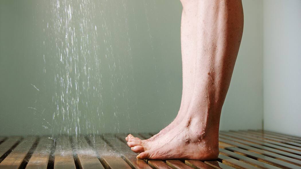 Die Kraft des kalten Wassers Füsse mit gespreizten Zehen unter der Dusche