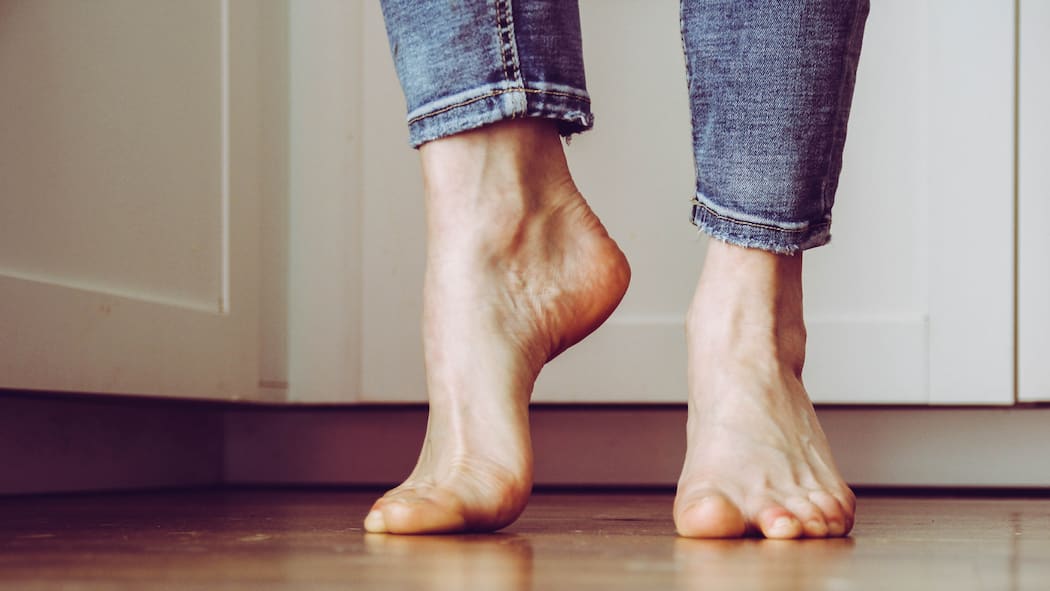 Diese Übungen helfen gegen Fussschmerzen Ein Mann steht mit nackten Füssen auf den Zehenspitzen