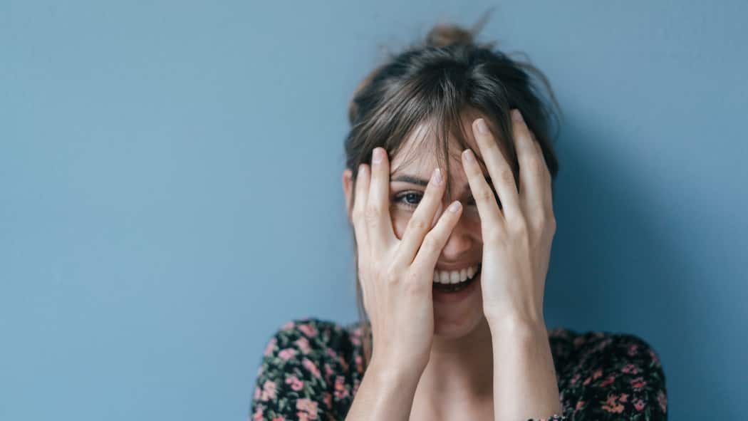 Wer lacht, lebt leichter Eine Frau lacht und bedeckt dabei ihr Gesicht teilweise mit ihren Händen