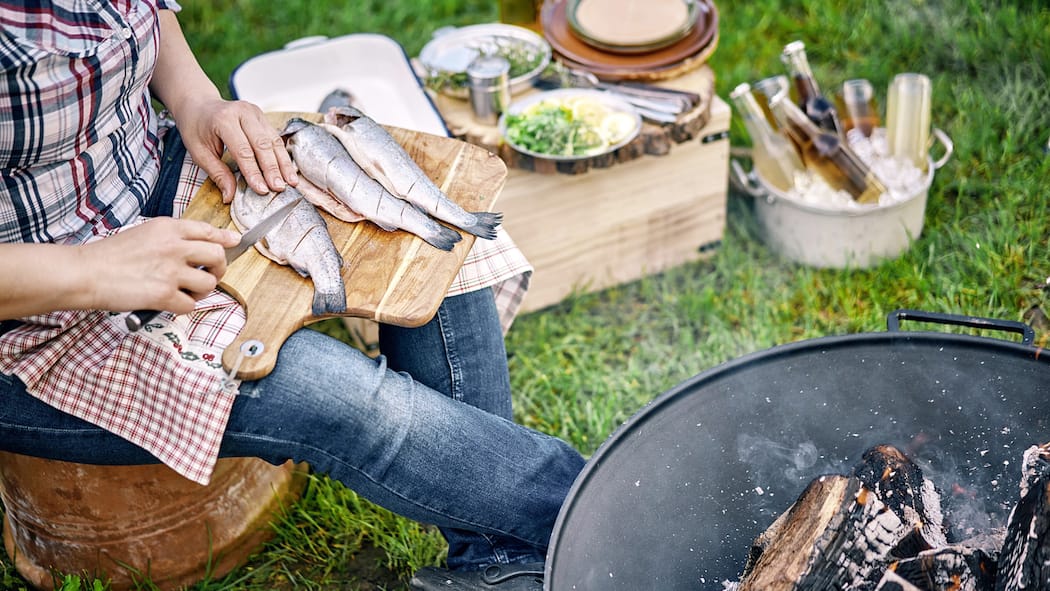So gibts keine Keime als Beilage Ein Mann bereitet Fisch an einem Grill zu.