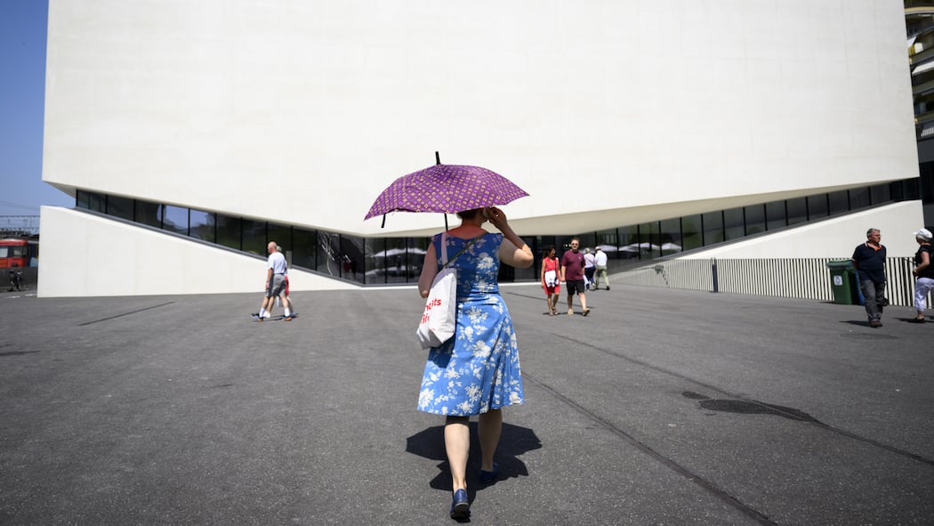 Kampf den Hitzeinseln Frau mit Sonnenschirm auf Asphaltplatz