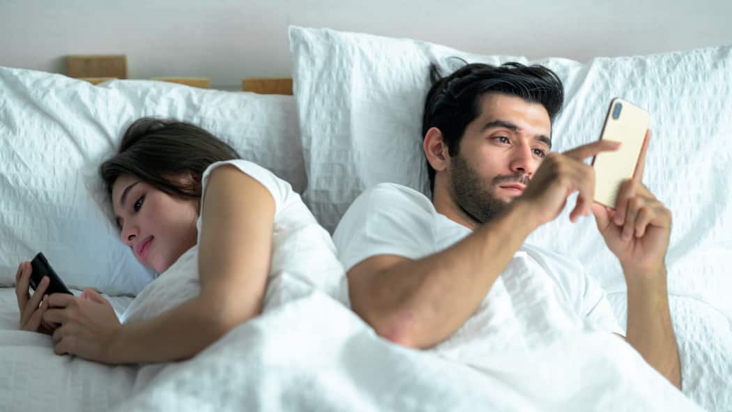 «Wir fühlen uns beide lustlos» Ein Paar liegt zusammen im Bett, beide sind mit ihrem Handy beschäftigt